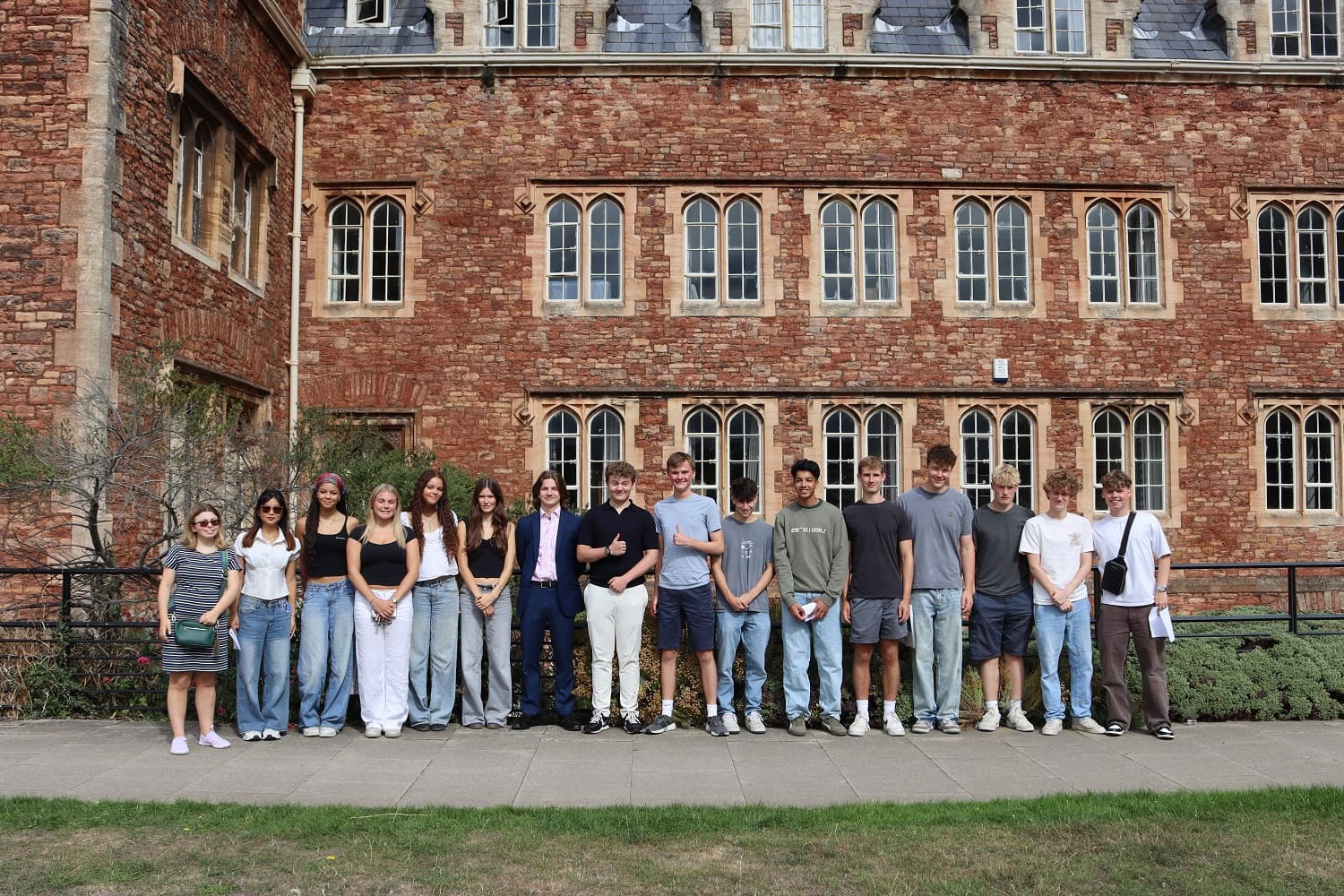 A group of people standing in front of a historic brick building with arched windows.