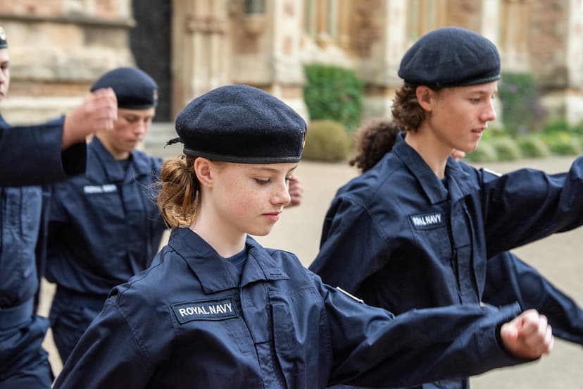 Royal Navy cadets in uniform march in formation outdoors, focusing on their synchronized movements.