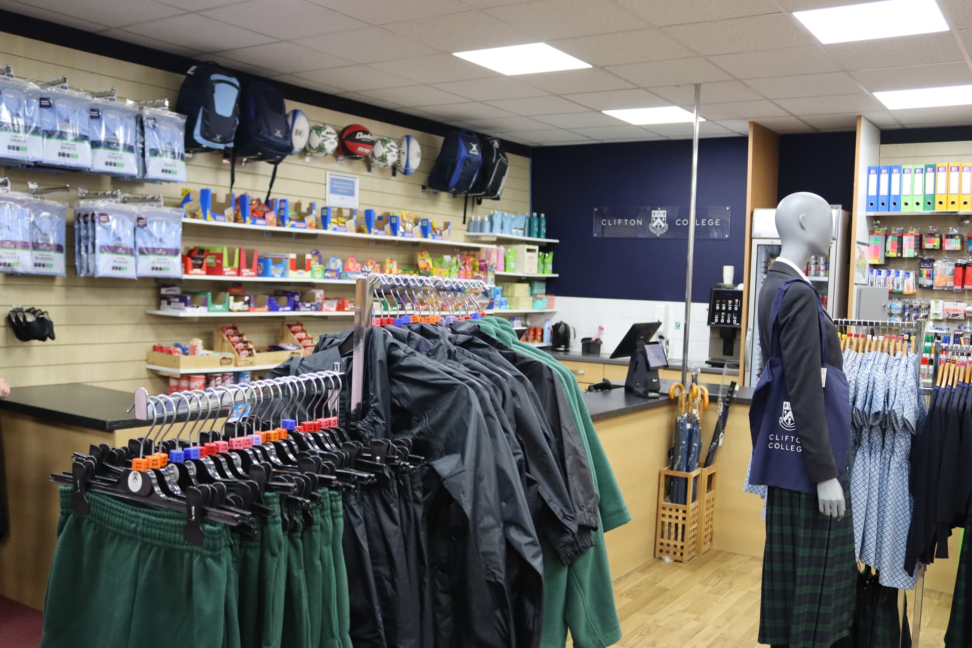 A school uniform shop with clothing racks, backpacks, stationery items, and a mannequin wearing a uniform.